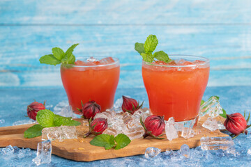 Iced roselle tea glass with fresh roselle fruit on wooden table for healthy herbal drink concept. herbal organic tea for good healthy.