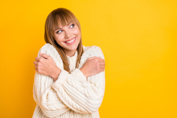 Photo of attractive person hugging shoulders toothy smile look empty space wear sweater isolated on yellow color background