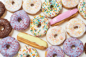 Sweet life. Top view of various colorful tasty and fresh donuts and eclairs, close up shot