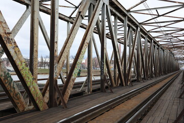 Stalowe zardzewiałe, elementy mostu kolejowego nad rzeką. 