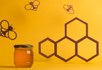 Honey jar among paper art, with paper cutter bees, and honeycombs. Healthy sweets organic food concept.