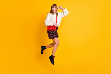 Full size profile portrait of attractive lady jumping fingers show v-sign near eye isolated on yellow color background