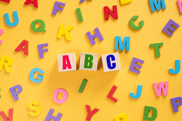 Alphabet on wooden tiles and ABC on a cube against yellow background. Concept of child leraning education development