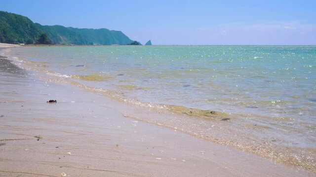 沖縄本島東部の美しい天然の「嘉陽ビーチ」の波打ち際。新型コロナの緊急事態宣言でほとんど人がいません。