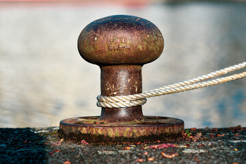 .Old metal and rusty polisher for mooring ships on the harbor wharf.