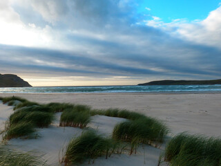 amazing sunset above the ocean at a beach in ireland with dunes anf grass