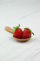 Stroberi or strawberries on wooden spoon with isolated white background. Bright photography concept, copy space for text.