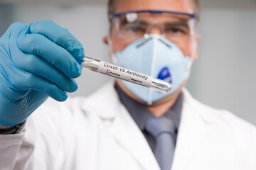 Doctor with medical face mask and medical gloves is handling a positive corona antibody test