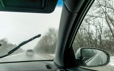 Car wipers wiping the windshield. Winter highway during snowfall