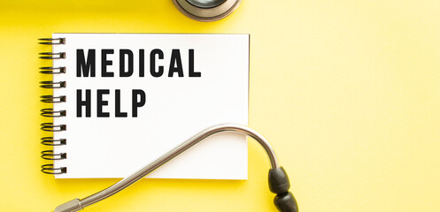 Text MEDICAL HELP on notebook with stethoscope on yellow background.