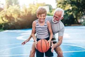 Fotobehang Grandfather and his grandson enjoying in beautiful sunny day and playing basketball. © hedgehog94
