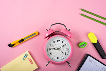 A table clock with a Marker pencils cutter and Sticky note on a pink background.