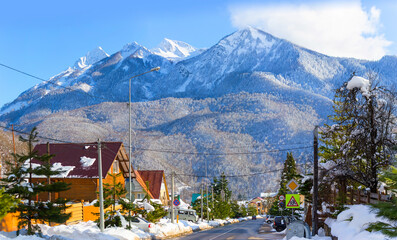 Krasnaya Polyana village, Sochi, Russia - Houses and a street on the background of the Caucasus Mountains