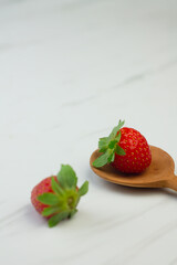 Stroberi or strawberries on wooden spoon with isolated white background. Bright photography concept, copy space for text.