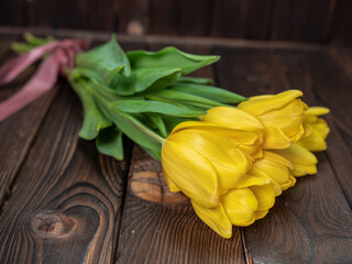 Yellow tulips lie on a wooden rustic table. Spring holidays concept background and mother day.
