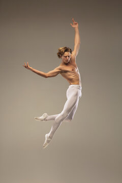 Aesthetic. Young and graceful ballet dancer isolated on studio background in flight, jump. Art, motion, action, flexibility, inspiration concept. Flexible caucasian ballet dancer, moves in glow.