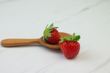 Stroberi or strawberries on wooden spoon with isolated white background. Bright photography concept, copy space for text.