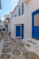 Traditional Cycladitic alley with a narrow street and  whitewashed houses with pots of flowers in Chora kythnos, cyclades, Greece.