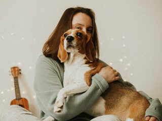 Happy young woman playing with her dog on a white background. Beagle dog with owner. Girl and dog...