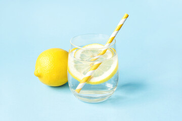 Glass of water with lemon on a blue background. Summer refreshing drink.