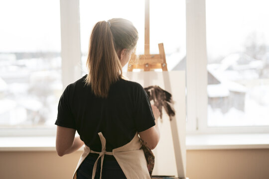 Smiling Female Artist Paints Picture On Canvas With Oil Paints.Close-up Of Confident Young Beautiful Woman Drawing Something On Canvas At Home. Finding Yourself And A Hobby In Isolation Or An Epidemic