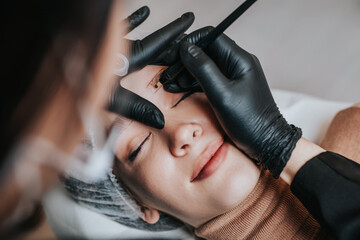 Eyebrows microblading concept, eyebrow permanent makeup procedure. Beauty expert is wearing shiled...
