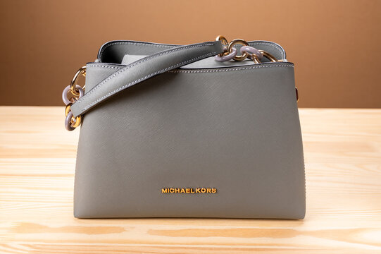 MOSCOW, RUSSIA - MARCH, 17, 2021: leather grey handbag Michael Kors on wooden table. Michael Kors brand of clothing, accessories and perfume