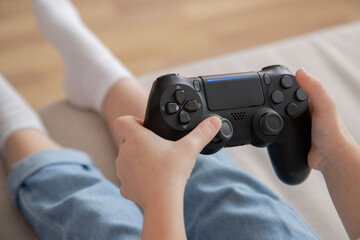 Close-up of a girl with joystick in hand, view from the back. A child plays video games. Leisure time at home.