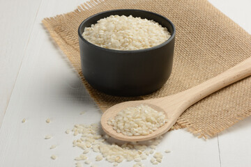 Arroz redondo en un bol de cocina negro en la mesa blanca