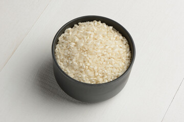Arroz redondo en un bol de cocina negro en la mesa blanca