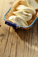 Cypriot semi-hard, fresh homemade unripened brined cheese. popular in the Levant, Greece and Turkey.Side view in wicker busket on rustic wooden background,copy space