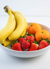 Plato blanco con bananas, naranjas y fresas