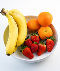 Plato blanco con bananas, naranjas y fresas
