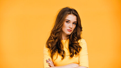 offended woman standing with crossed arms isolated on yellow