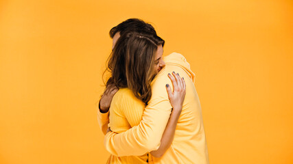 young man and woman hugging isolated on yellow