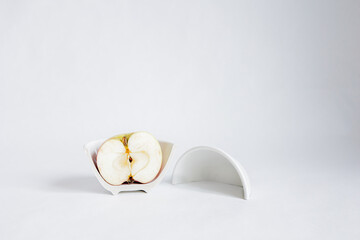 Sliced ​​half of an apple in a broken half of a ceramic small platter on a white background. Place for text. Concept.
