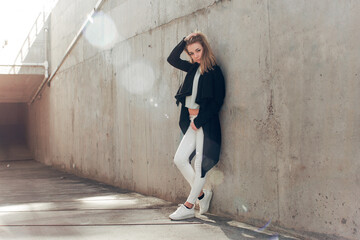 Fototapeta premium beautiful blonde in a black cape posing against the background of a concrete wall