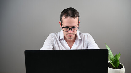 Young man in glasses works at the computer, front view