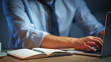 partial view of businessman using laptop near notepad