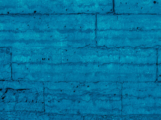 Brickwork of bright blue geometric horizontal bricks bonded with cement grout between square stones. Wall exterior. Background