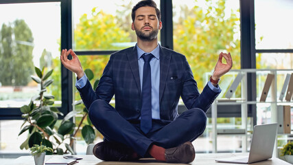 businessman in suit meditating on desk in office