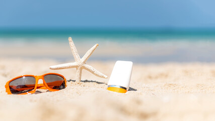 Fototapeta na wymiar Protective sunscreen or sunblock and sunbath lotion for healthy care skin woman in white plastic bottles with starfish on tropical beach, summer accessories in holiday, copy space for text banner.