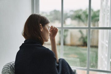 sad woman at home near the window pensive look problems