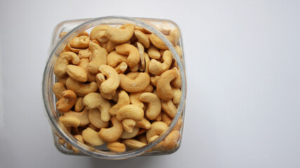 In a jar, fried cashews without shells. Top view of cashew nut isolated on white background. Set or collection. Selective focus.