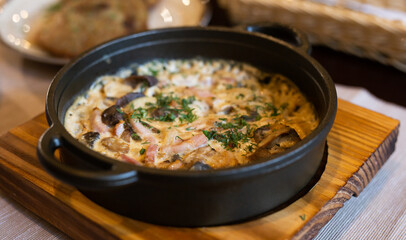 fried pieces of meat with vegetables and bechamel sauce baked in cast iron skillet