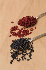 Black and red dried barberry in spoons