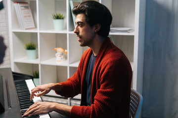 Portrait of professional music teacher explains to student how to sing during lesson. Musician male practicing lesson at home in living room. Concept of music education.