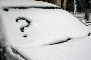 A car under the snow and a question mark in the windshield.