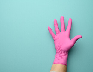 female hand in a pink latex glove on a blue background, palm open