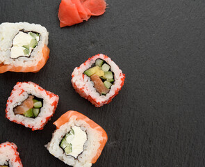 california sushi with red tobiko caviar and slices of philadelphia sushi on black slate board